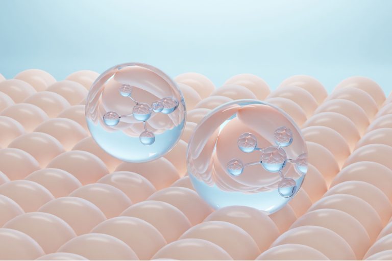 Dos burbujas translúcidas flotan sobre un fondo de tono beis rosado, simulando activos biotecnológicos avanzados entrando en la superficie de la piel.